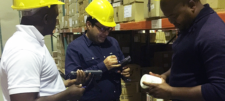 Three men stand in a warehouse