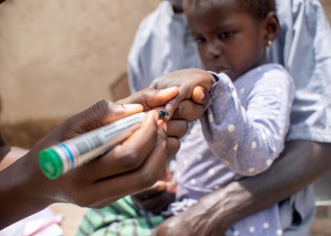 A child in Ghana has her finger marked with black ink to indicate that she received her dose of SPAQ.